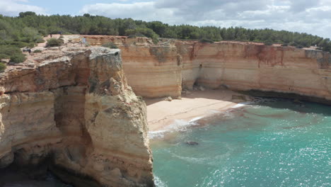 antena de una pequeña y hermosa playa de arena rodeada de altos acantilados