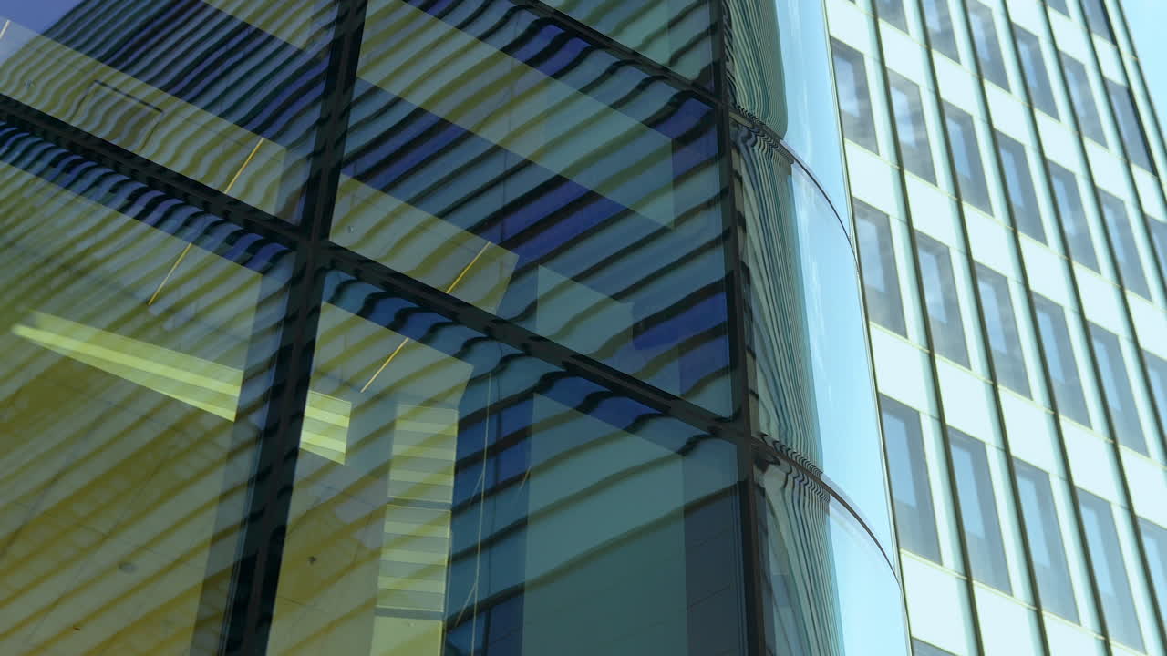 Esquina de un edificio moderno con cristales reflectantes contra un cielo nublado