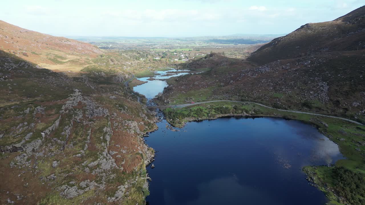 Wide panning aerial shot of Gap of Dunloe, Bearna or Choim&iacute;n, mountain pass in County Kerry, Ireland, with a bridge over the river Loe