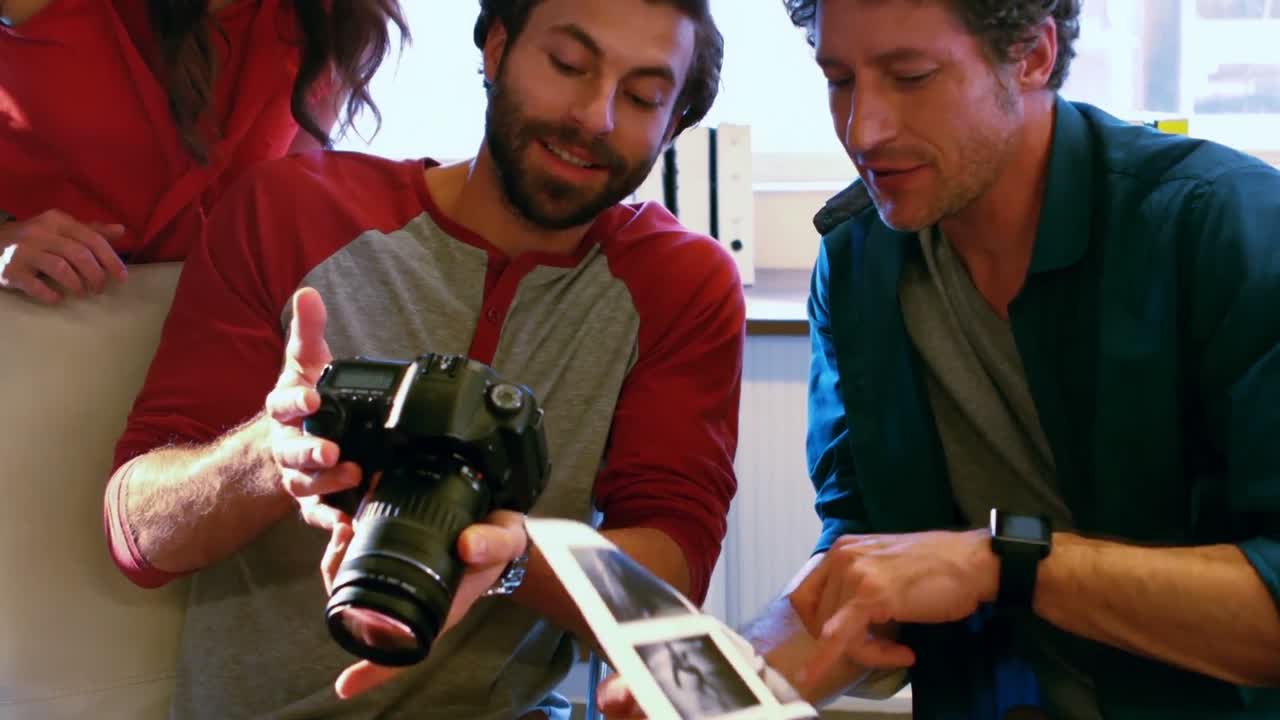diseñadores gráficos que muestran imágenes de sexo masculino a sus compañeros de trabajo en la cámara