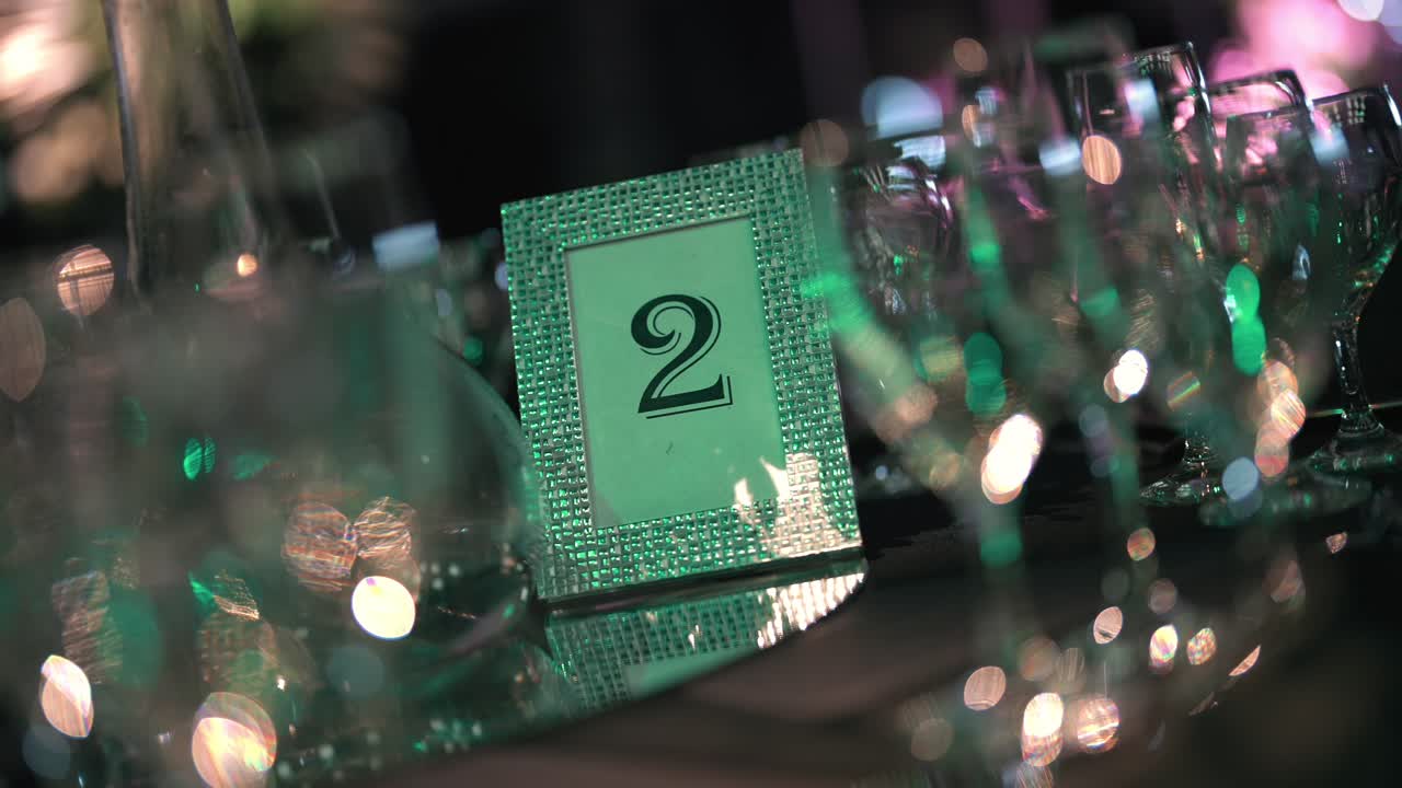 Mesa elegante com o número 2 e utensílios de vidro cintilantes em evento