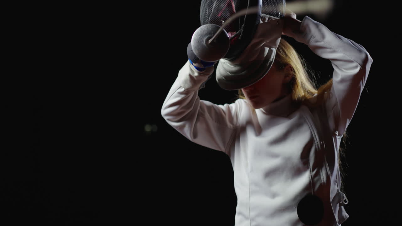 una mujer joven en un uniforme de esgrima practicando con una lámina.