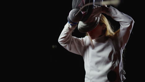 a young woman in a fencing uniform practicing with a foil.