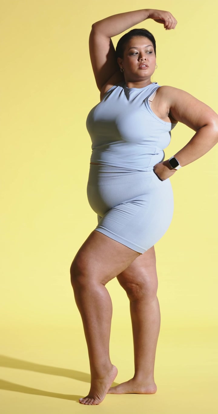 Video verticale: Donna che entra in un set da studio, girando il braccio con un ampio gesto per mostrare uno smartwatch da fitness.