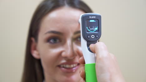 Hand of an ophthalmologist holds a device attached to a patient's forehead. Young woman at oculist's check up. Close up.