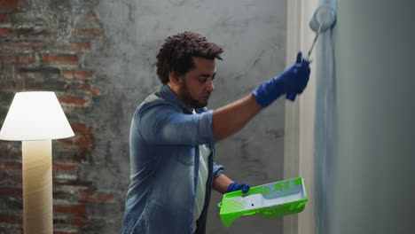 African-American-painter-applies-paint-from-tray-on-wall