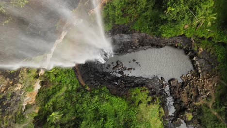 Unique-revealing-view-of-a-waterfall-cascading-down-into-a-natural-swimming-hole-deep-in-a-tropical-rainforest