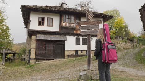 young blonde musician reads direction signpost in bulgarian village