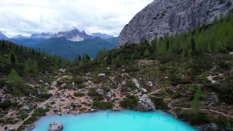 hikers exploring turquoise lake sorapis in dolomiti, italy