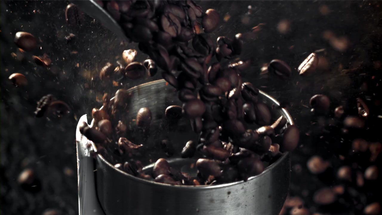Movimento rallentato di chicchi di caffè tostati che si versano in un macinacaffè