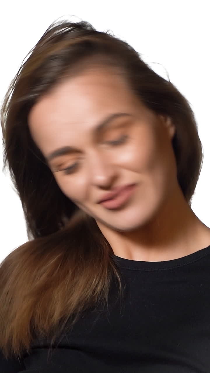 Beautiful woman waving her hair. Laughing woman covers her face with long hair. Shaking her hair. Slow motion. Vertical video
