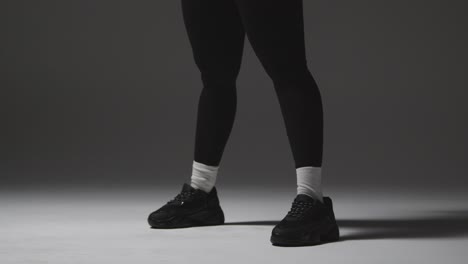 fotografía de estudio de una mujer con ropa de gimnasia haciendo ejercicio con pesas de kettlebell 1