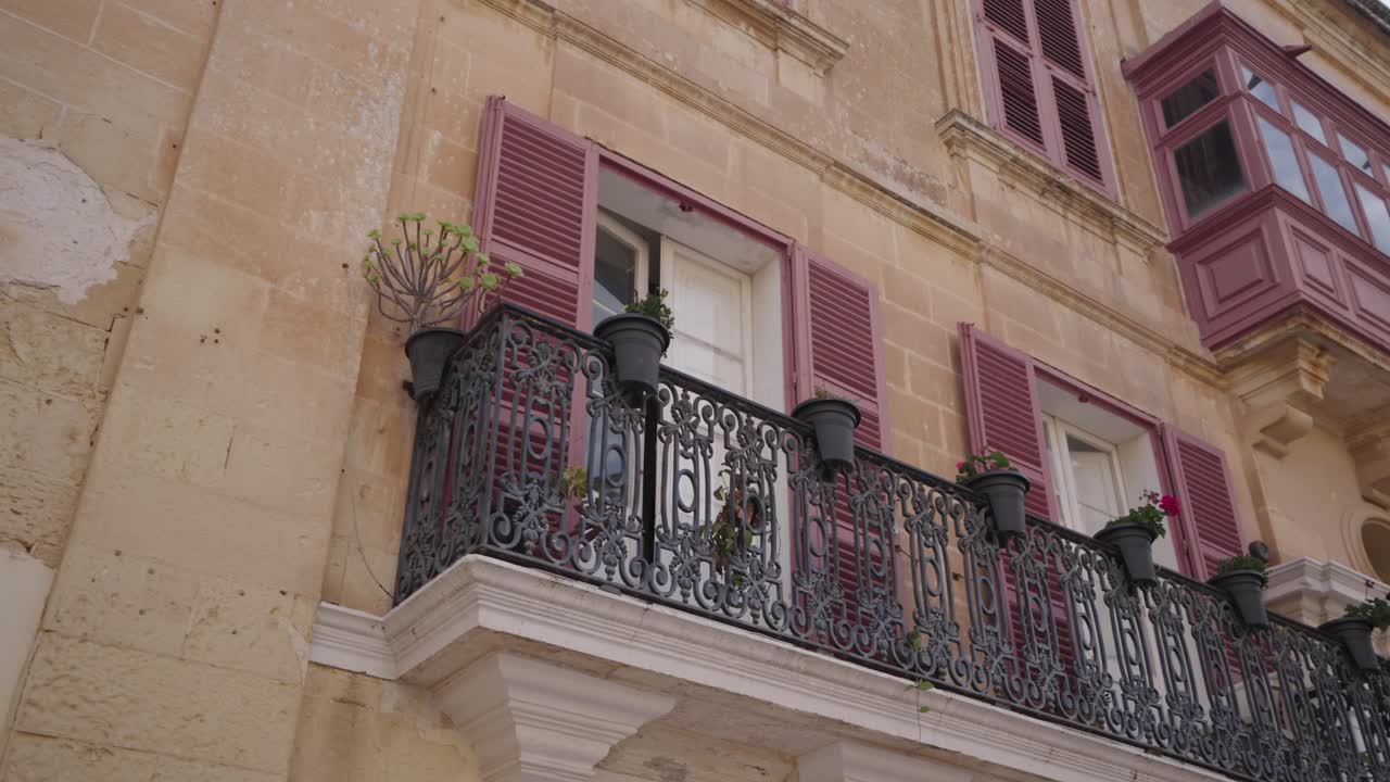 Charming historic limestone buildings with colourful shutters in Maltese town