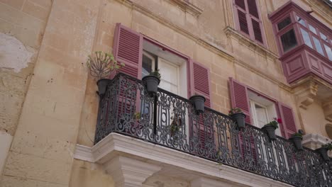 charming historic limestone buildings with colourful shutters in maltese town