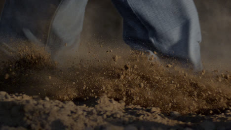 cowboy boots kicking up dirt while backing up from a bull during a rodeo event