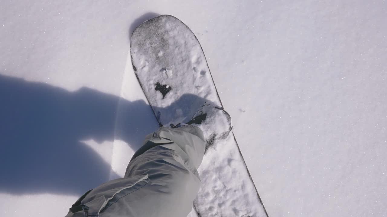 punto de vista de arriba hacia abajo de una tabla de snowboard que se mueve en polvo de nieve