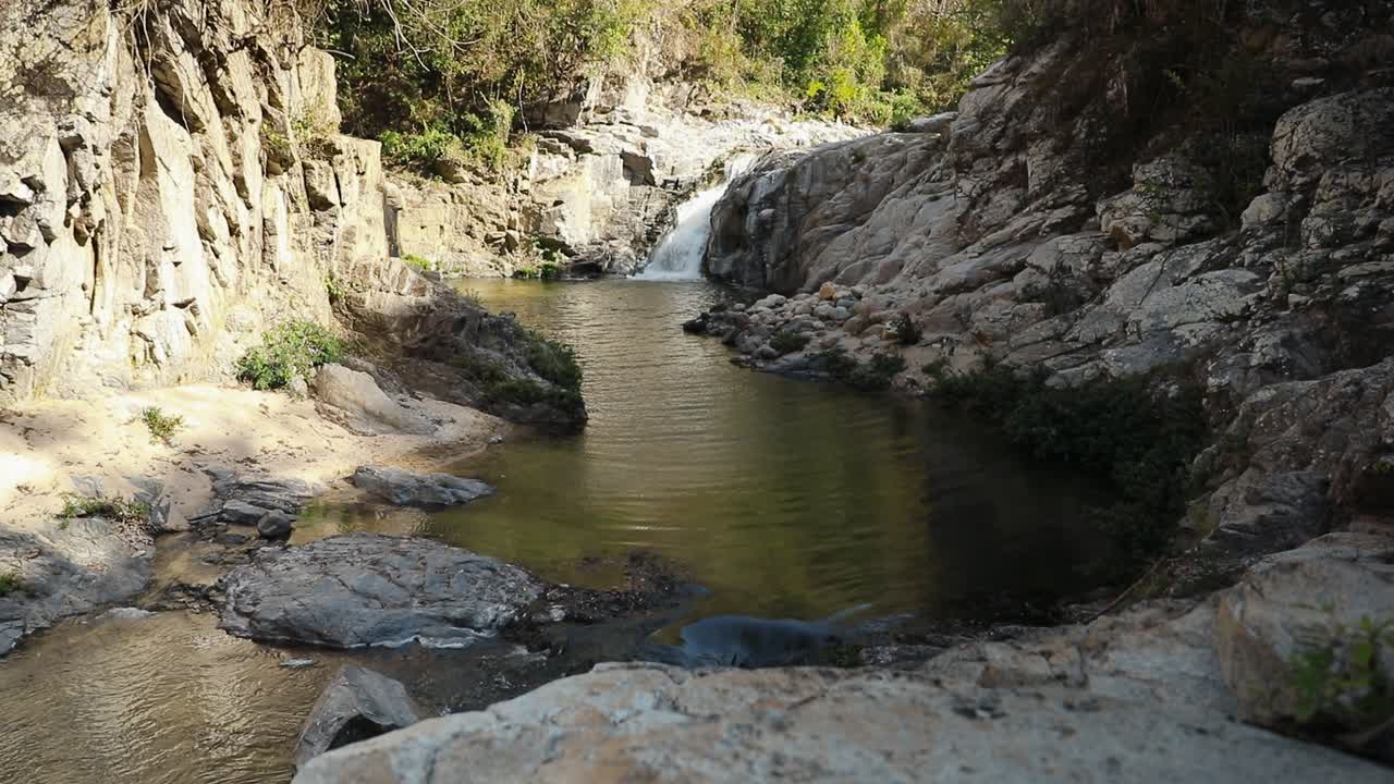 Ampia veduta di una cascata che si riversa in una pozza calma circondata da pareti rocciose di canyon a Yelapa, Jalisco, Messico.
