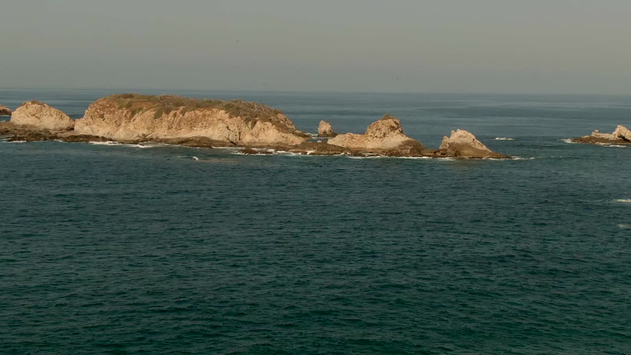 Volando sopra il mare verso l'isola rocciosa a El Faro de Bucerias, in Michoacán, Messico.