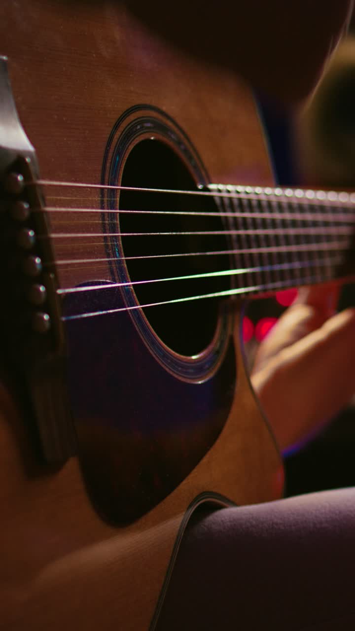 Close Up of Hands Playing Acoustic Guitar with Colorful Lights