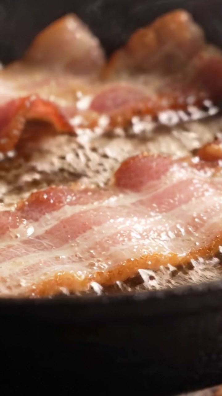 Sprød bacon, der steger til perfektion på en varm pande, fremviser den sprøde tekstur og det lækre fedt, der forbedrer smag og appetit.