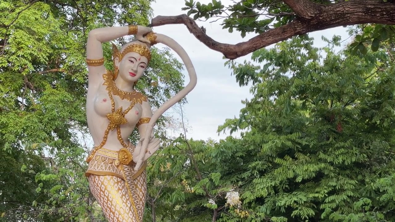 Statua tradizionale thailandese circondata da una vegetazione lussureggiante ad Ayutthaya, Thailandia