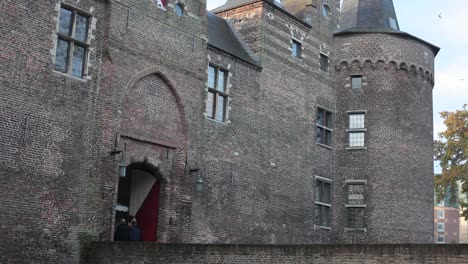 People-walking-over-castle-bridge,-entering-castle,-birds-flying-by