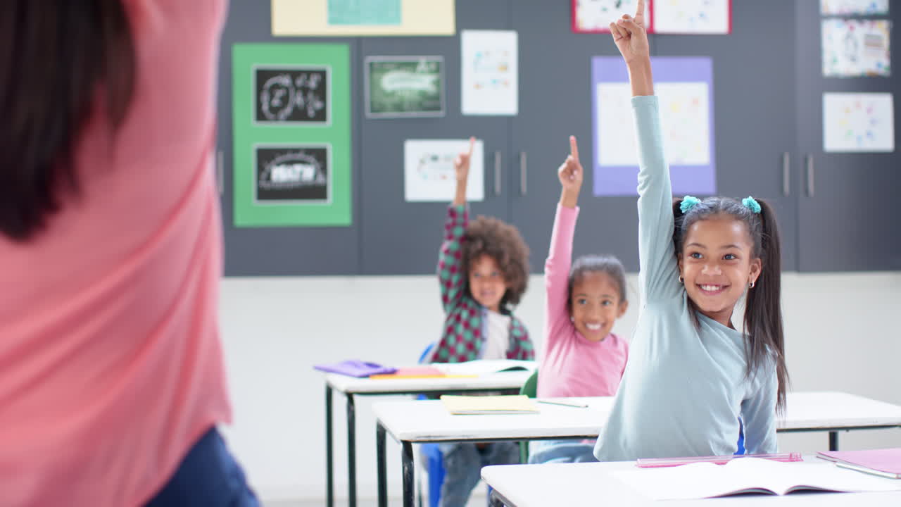In school classroom, raising hands and smiling, students participating in lesson