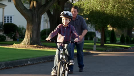father teaching his son how to ride a bike