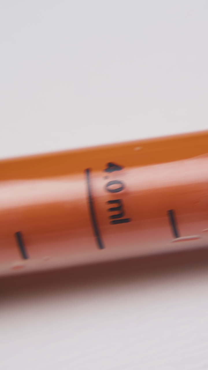 motion along new dosage syringe with orange element and scale lying on white background extreme close view