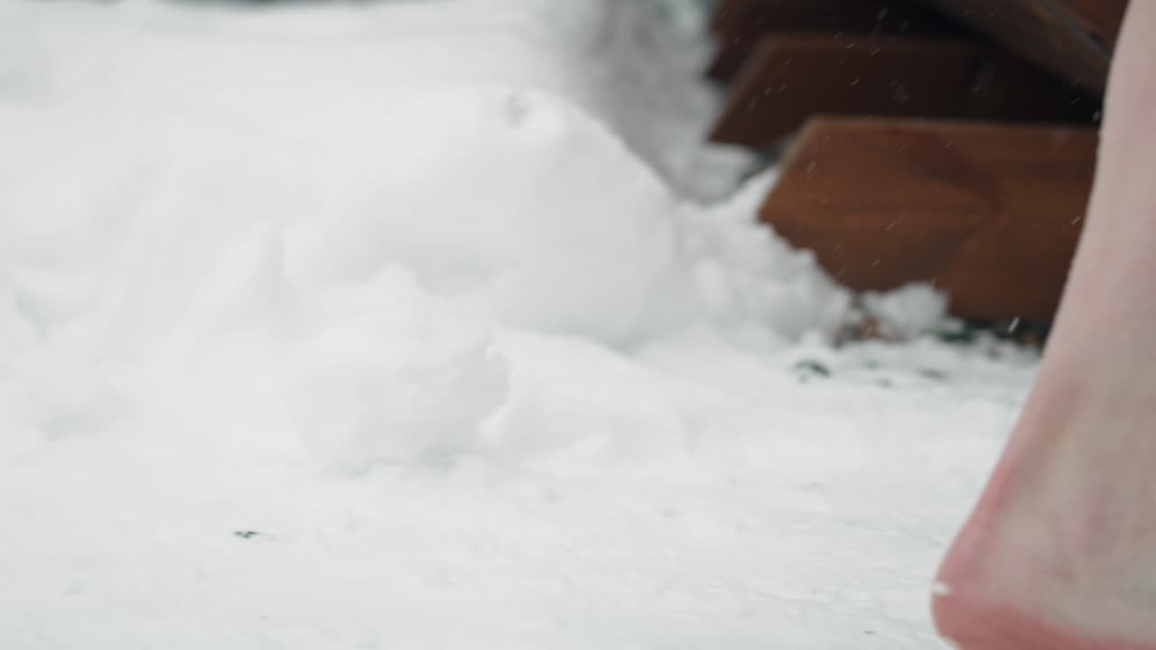 Woman's feet come out of the frozen water and enter the sauna.