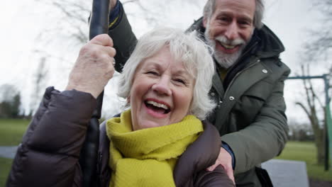 senior couple having fun playing on zip wire in park playground