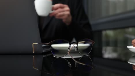 woman working at laptop with coffee and glasses