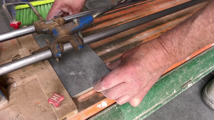 Person is adding peace of tile to manual tile cutter, process of slicing over tiles and splitting it into peaces, tiles craftsmanship concept