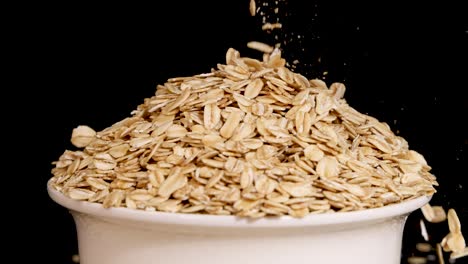oat grains cascade into a white bowl against a black background, highlighting texture and motion in a 13-second video