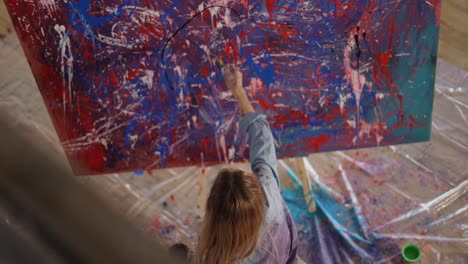 woman uses brush and black paints splashing gesture on canvas, footage from above