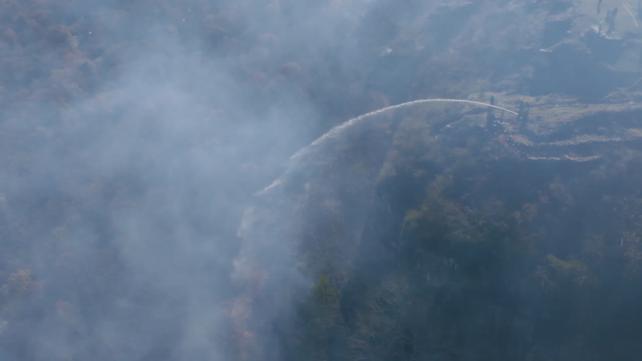 아웃 마운틴 (lookout mountain) 의 산불에 물을 뿌리는 절벽에 있는 소방관들의 연기를 통해 느린 움직임의 공중 영상.
