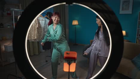 two friends in pajamas having fun on a video call