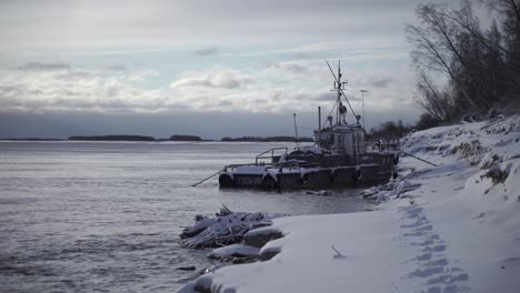 abandoned tugboat on a frozen riverbank in winter