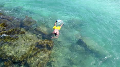 man snorkeling in maldives crystal clear waters, close aerial pan 4k