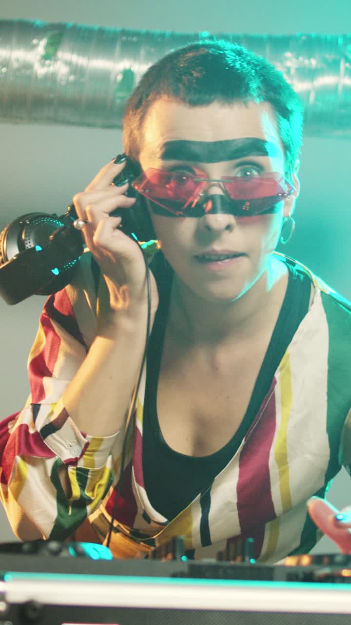 Vertikal video. En glad artist jobber som DJ med elektriske platespillere
