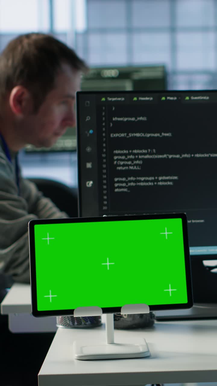 Green Screen Tablet on Desk with Programmer Working in Background