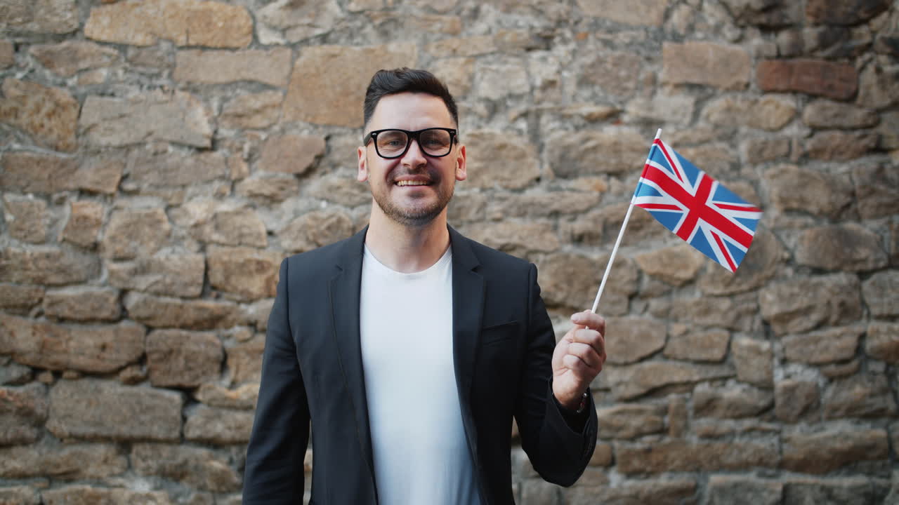 Man holding British flag in front of a stone wall