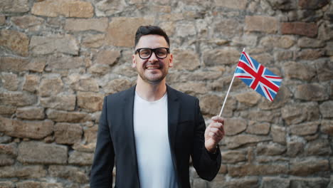 man holding british flag in front of a stone wall