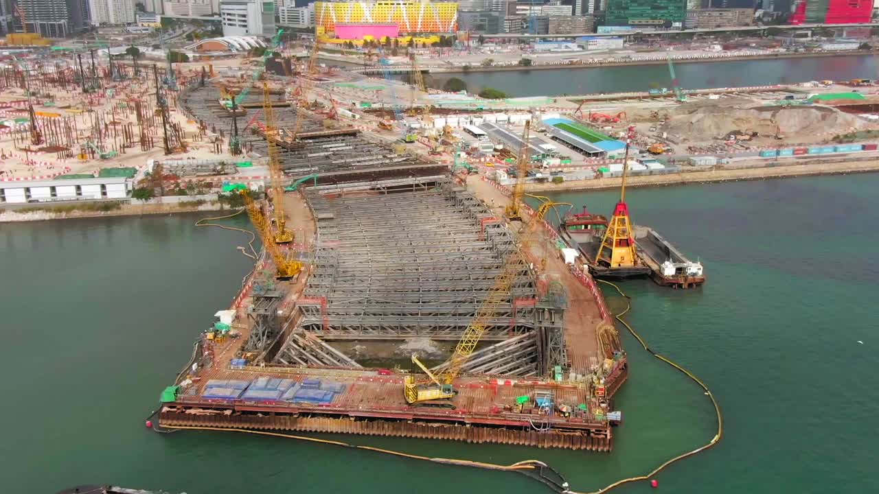 Time lapse of Converting an old runway strip into a Housing and business district in downtown Hong Kong, with vast infrastructure development land and underwater tunnel laying operation, Aerial view.