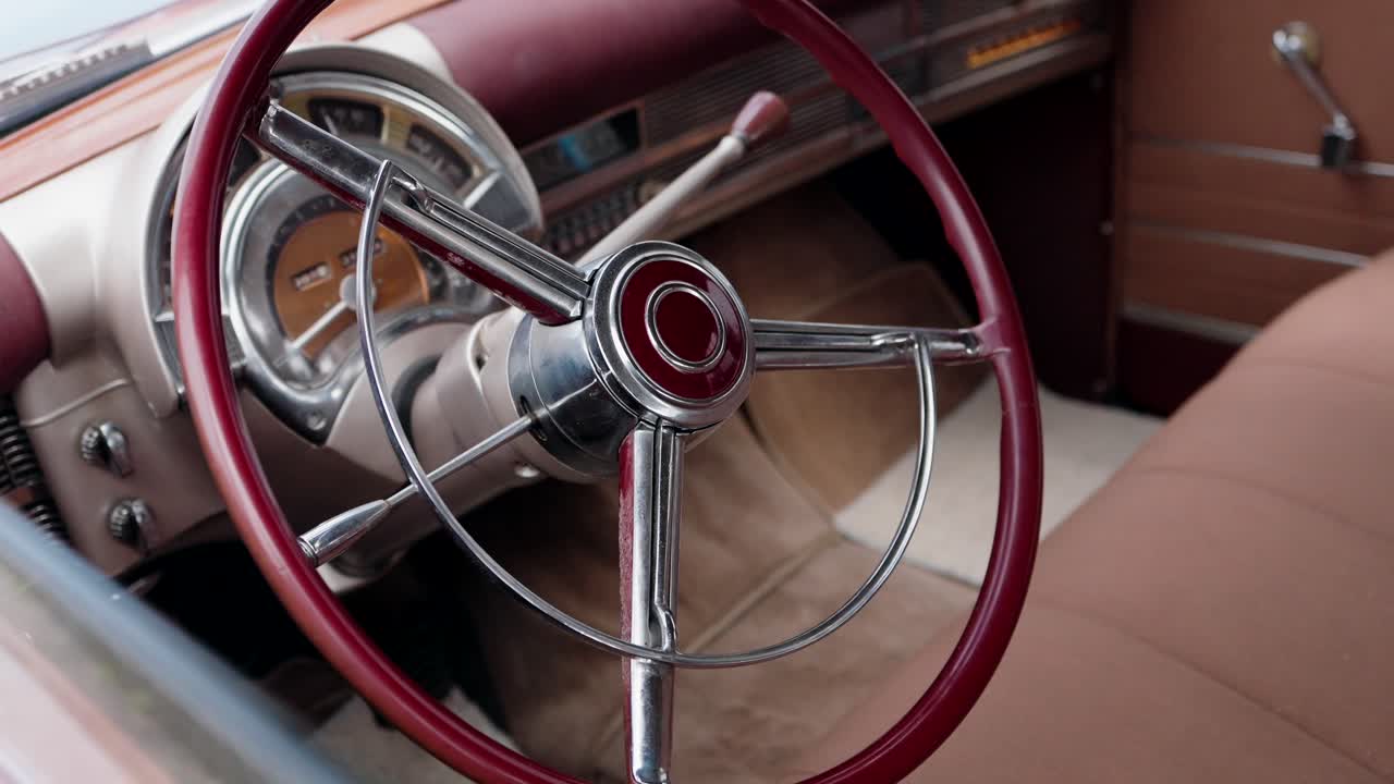 Close up of red steering wheel in vintage car interior with classic dashboard