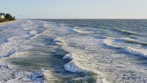 Drone-4K-rising-pullback-over-beach,-green-blue-water-waves