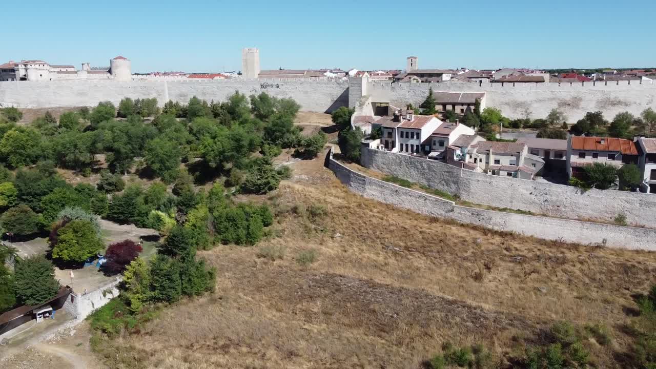 murallas medievales, castillo y casco antiguo tradicional rodeado de árboles, hierba seca, cielo azul y luz del día