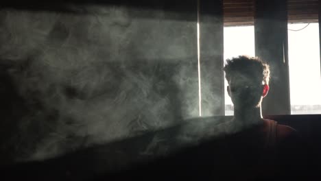 man surrounded by smoke in slow motion in dark