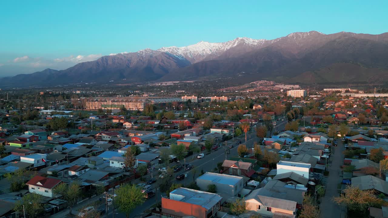 Statisk luftfoto af et boligområde i Santiago med sneklædte Andesbjerge i den gyldne time. Santiago, Chile.