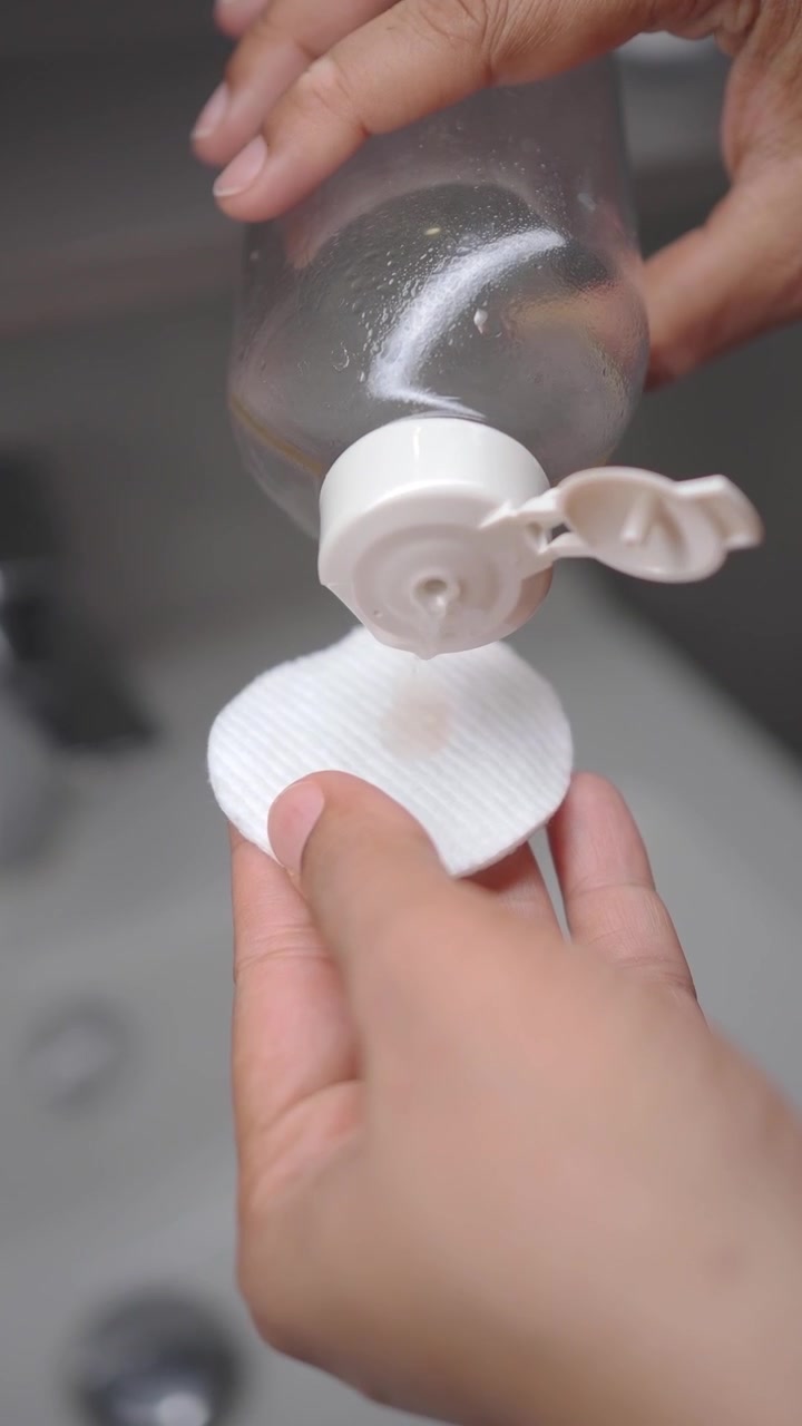 Pouring Micellar Water onto a Cotton Pad for Skincare Routine